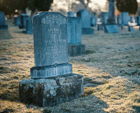 A gravestone illuminated by sunlight in a graveyard.